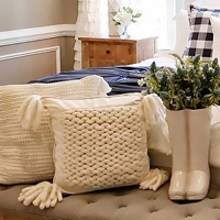 Image of farmhouse decor featuring knit pillows and a tufted school