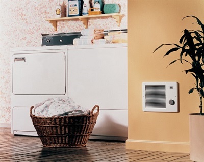 Inline exhaust fan in the wall next to a washing and drying machine and a basket of laundry.