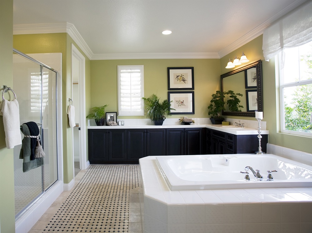 Large green bathroom with big tub, corner cabinets, full-length sliding door shower, and an open window.