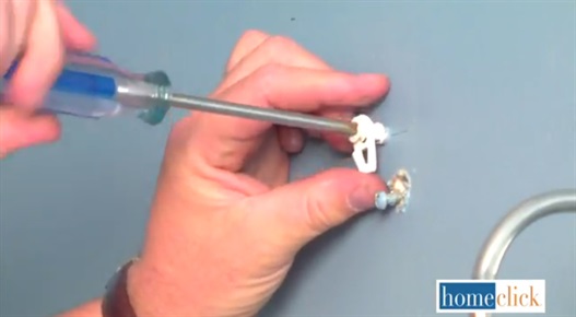 Using a screwdriver to drive in anchoring screws into the previously made holes