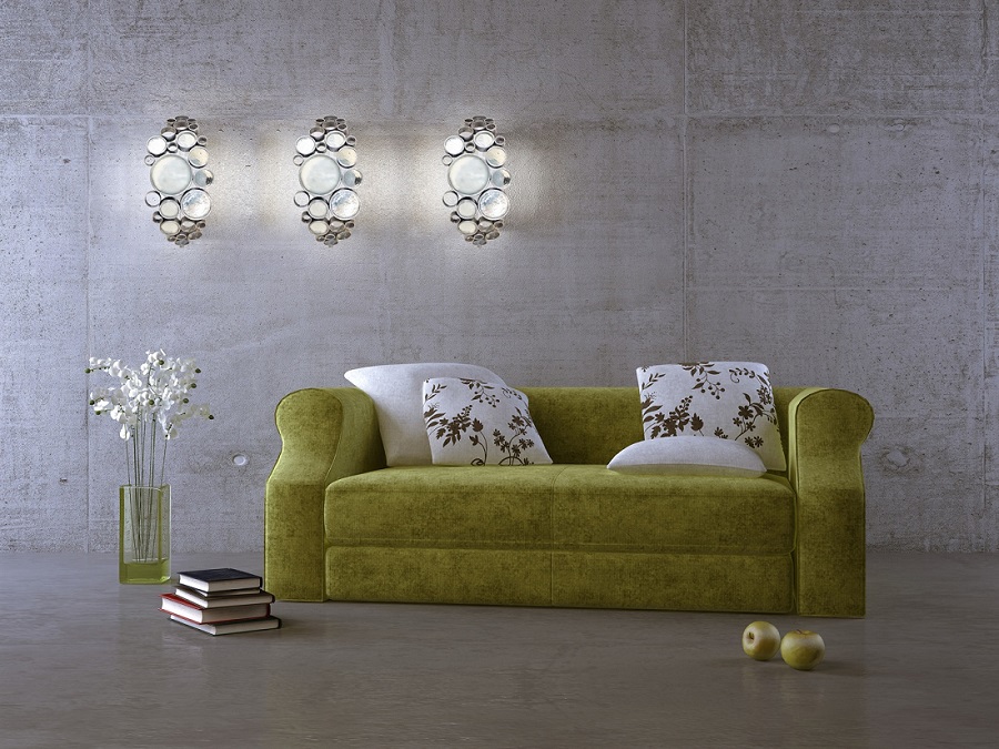 Green couch in concrete room with matching green apples and decor mounted light fixtures